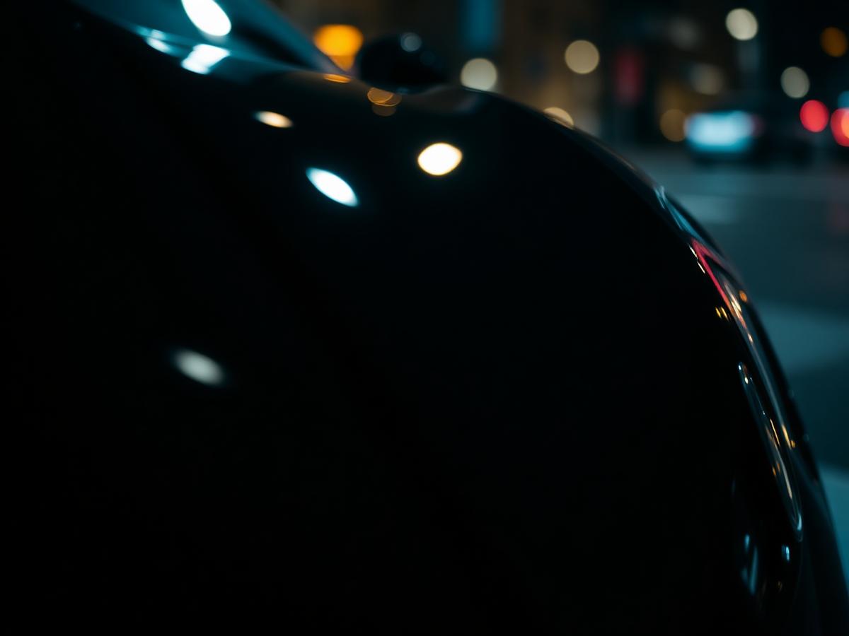 Close-up of a luxury automotive paint finish reflecting city lights